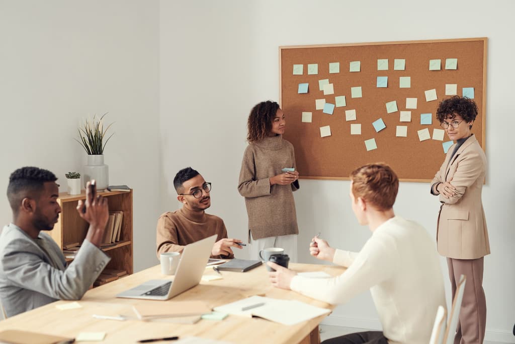 Colleagues gathered around a corkboard covered in sticky notes during a planning session