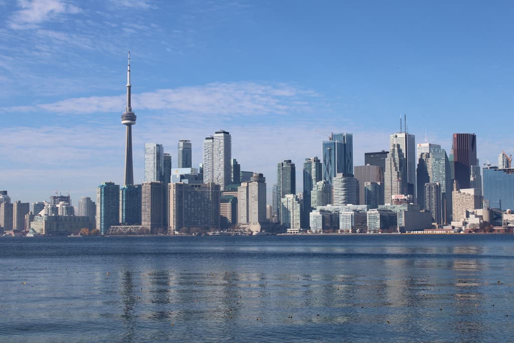 The Toronto skyline and CN Tower seen across Lake Ontario under a blue sky